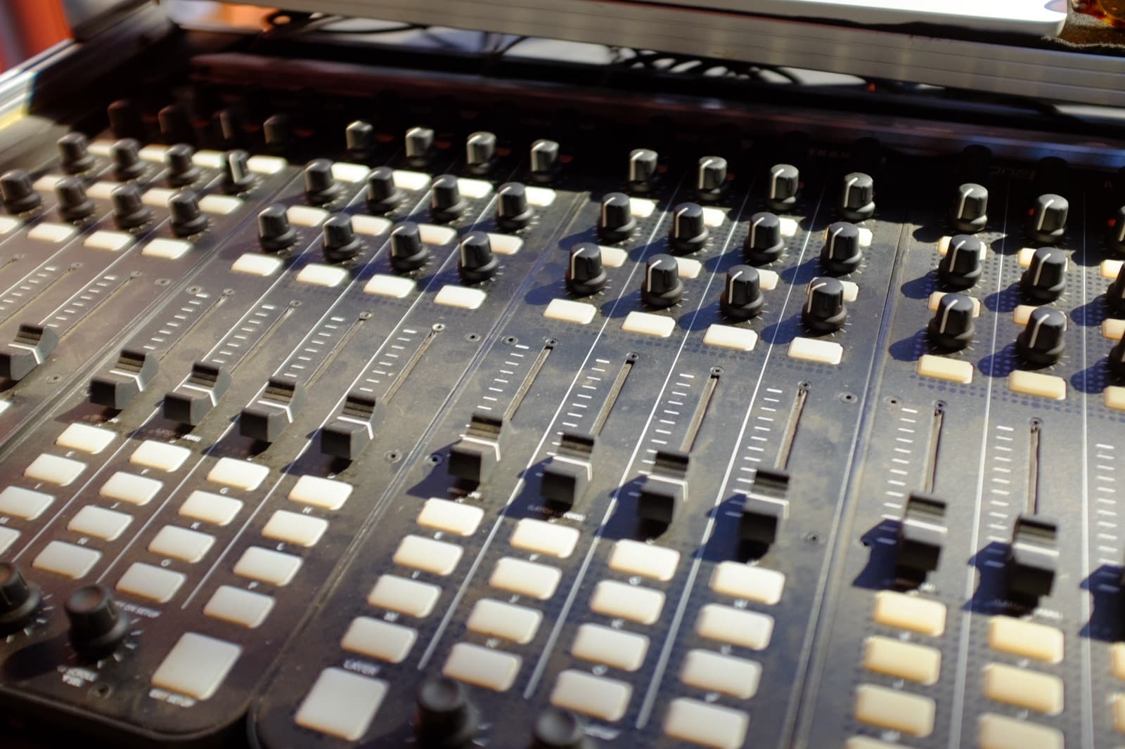 A lighting control surface in close-up: banks of faders, rotary knobs, and backlit buttons.